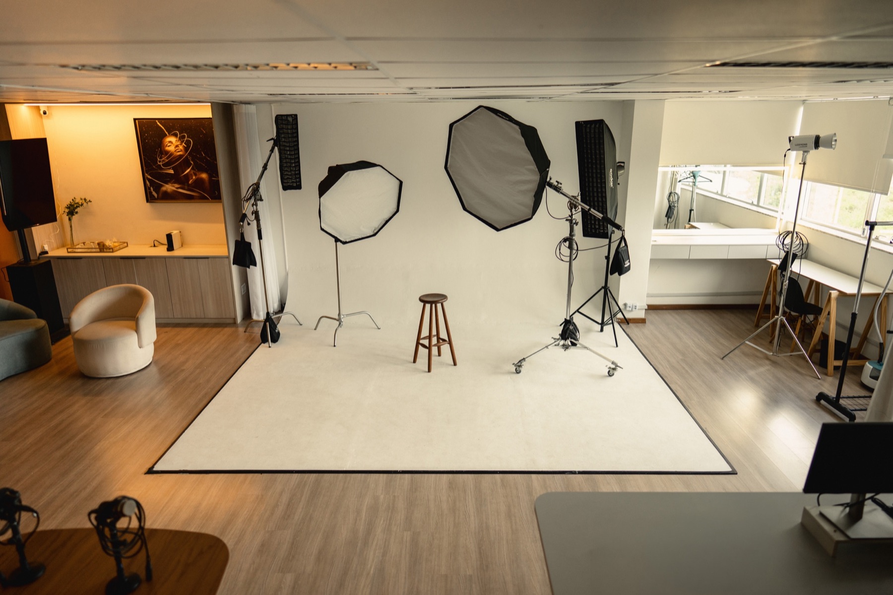 Vista ampla do Estúdio 403: ciclorama branco com softboxes montadas, lounge e camarim ao fundo