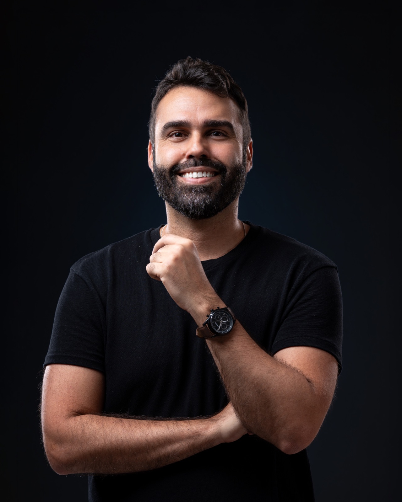 Thiago Bomfim, de camiseta preta, sorrindo, em retrato de estúdio