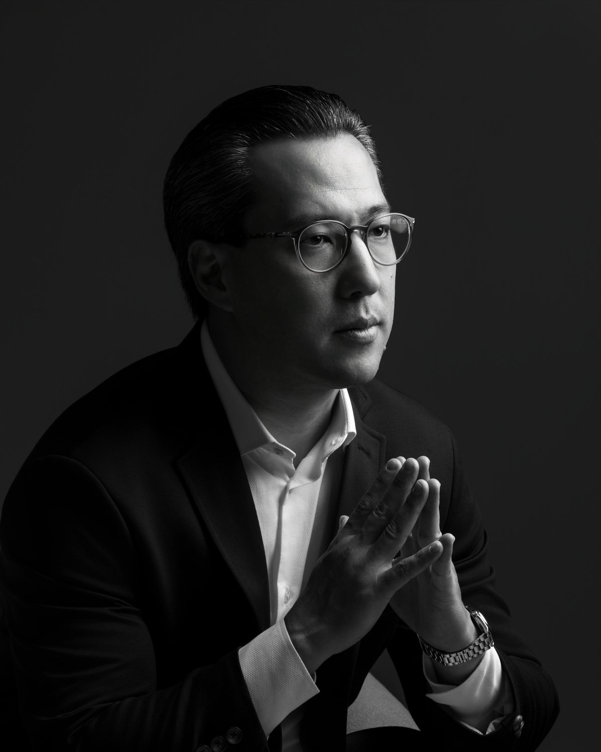 Retrato corporativo em preto e branco: homem de óculos com luz recortada
