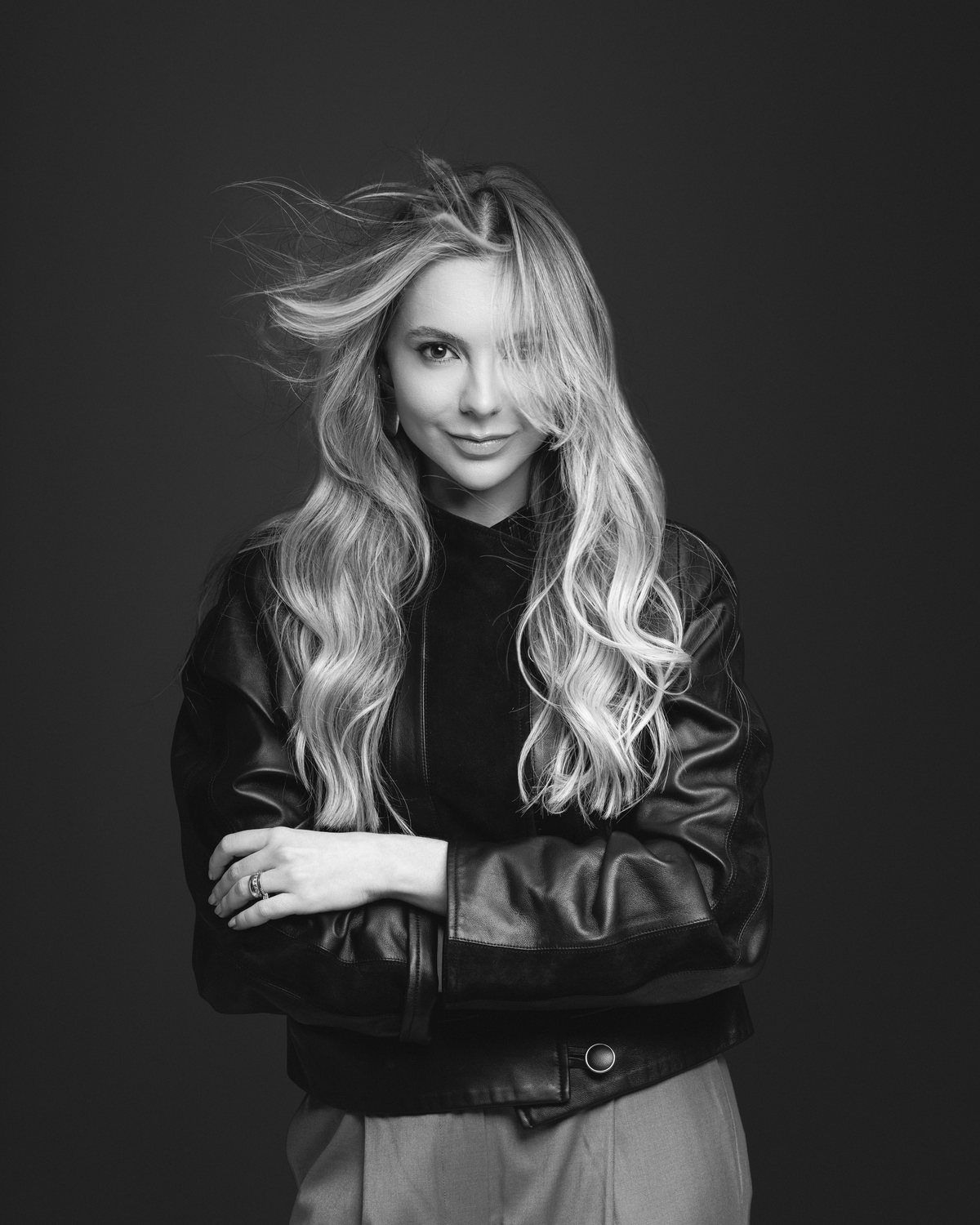 Retrato em preto e branco de mulher loira de jaqueta de couro, com o cabelo ao vento